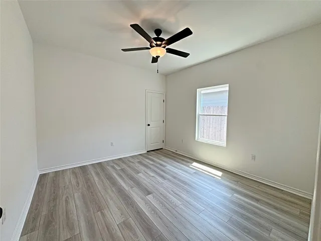 an empty room with wooden floor a ceiling fan and wooden floor