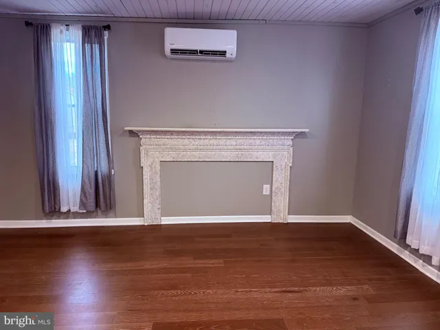 an empty room with wooden floor fireplace and windows