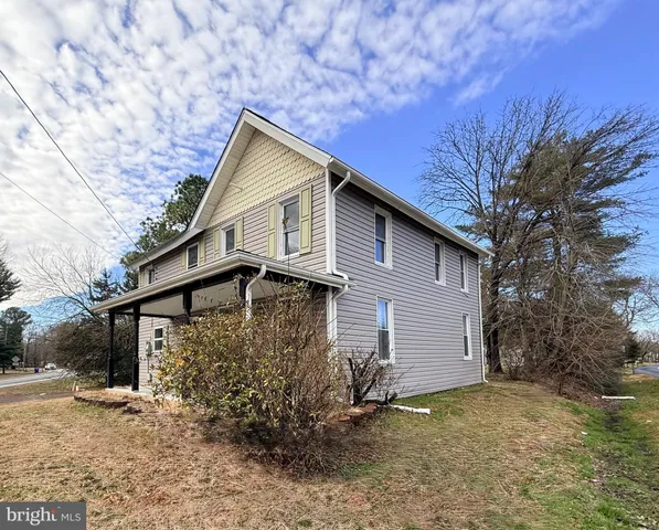 a front view of house with yard and trees in the background