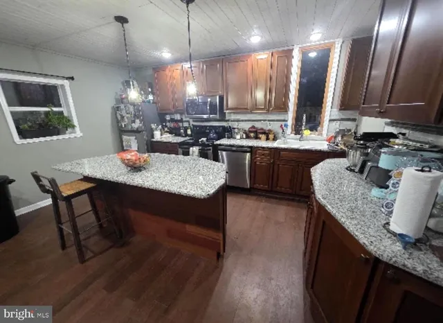 a kitchen with granite countertop kitchen island stainless steel appliances sink stove dining table and chairs