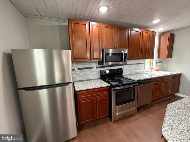 a kitchen with stainless steel appliances granite countertop a refrigerator a stove a sink and a microwave