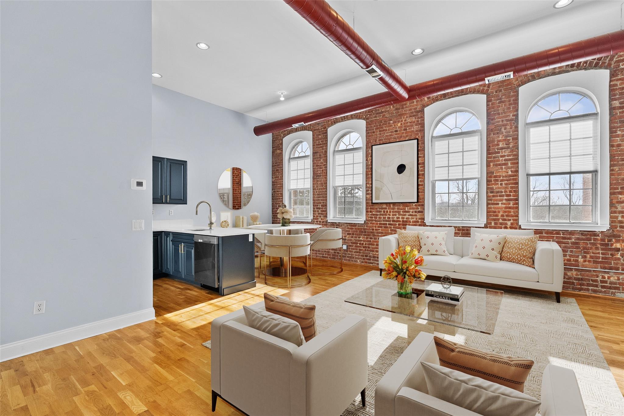 Living room with brick wall, light wood finished floors, beamed ceiling, and recessed lighting