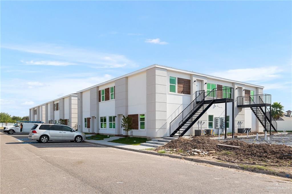 View of building exterior featuring stairway and uncovered parking