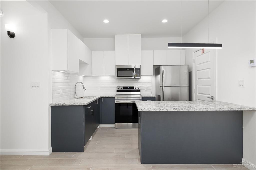 901 East Yuma Avenue, Unit 1901 McAllen, TX 78503 - Photo 5 of 9 Kitchen with appliances with stainless steel finishes, light stone counters, backsplash, white cabinetry, and recessed lighting