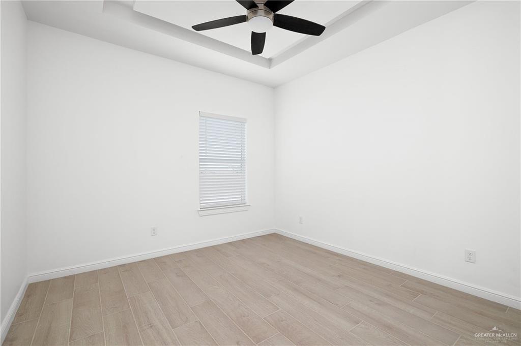 901 East Yuma Avenue, Unit 1901 McAllen, TX 78503 - Photo 6 of 9 Empty room with a raised ceiling, wood finished floors, and a ceiling fan