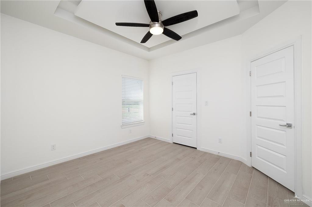 901 East Yuma Avenue, Unit 1901 McAllen, TX 78503 - Photo 8 of 9 Unfurnished bedroom with a tray ceiling, light wood-type flooring, and ceiling fan