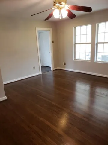 an empty room with wooden floor chandelier and windows
