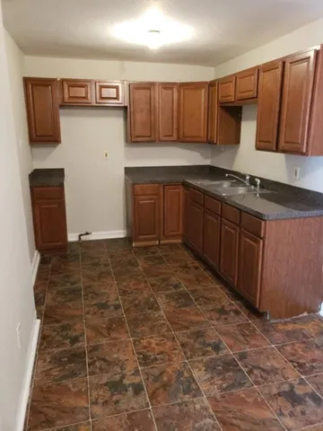 a kitchen with granite countertop a stove a cabinets and a sink