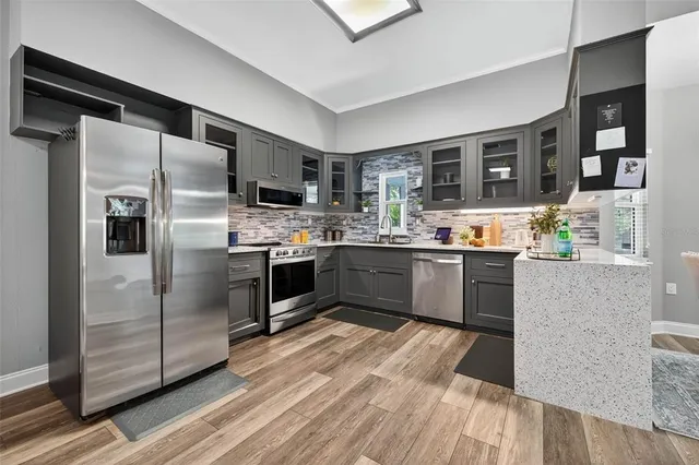 a kitchen with stainless steel appliances granite countertop a refrigerator a stove and a sink