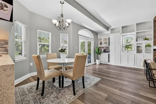 a dining room with wooden floor a chandelier a wooden table and chairs