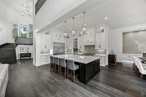 a large kitchen with cabinets chairs and wooden floor