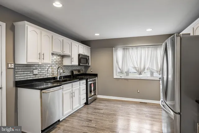 a kitchen with stainless steel appliances granite countertop a stove a sink and white cabinets