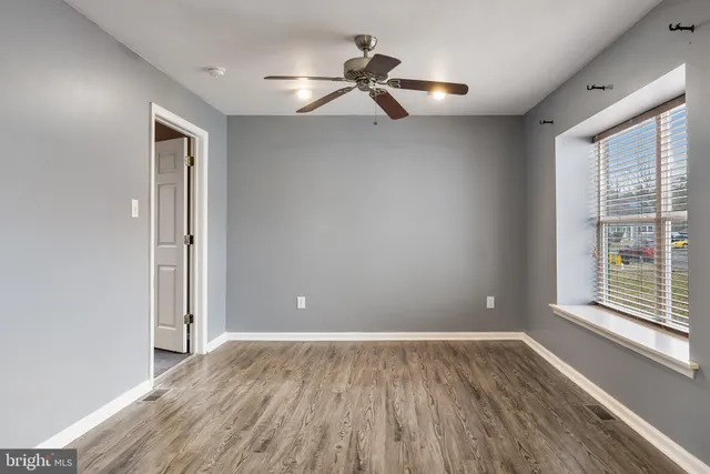 a view of empty room with wooden floor and fan