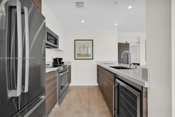 a living room with stainless steel appliances kitchen island granite countertop a sink a counter space and a view of living room