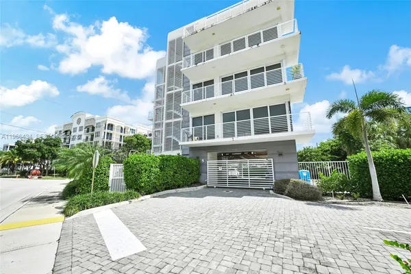 a view of a multi story residential apartment building with yard and tress in front of it
