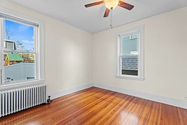 a view of empty room with wooden floor and fan