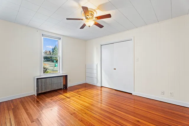 an empty room with wooden floor and chandelier fan
