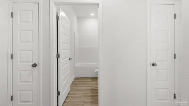 a kitchen with granite countertop a stove top oven a sink a refrigerator and white cabinets with wooden floor