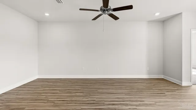 a view of a hallway with wooden floor and a bathroom
