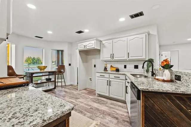 a kitchen with granite countertop a sink stove and cabinets