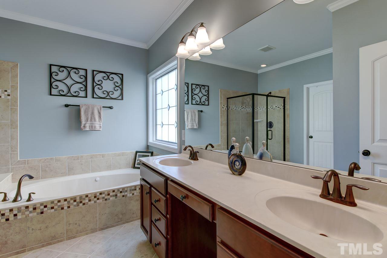 4001 Red Grape Drive Raleigh, NC 27607 - Photo 15 of 25 a bathroom with a tub a double vanity sink and mirror