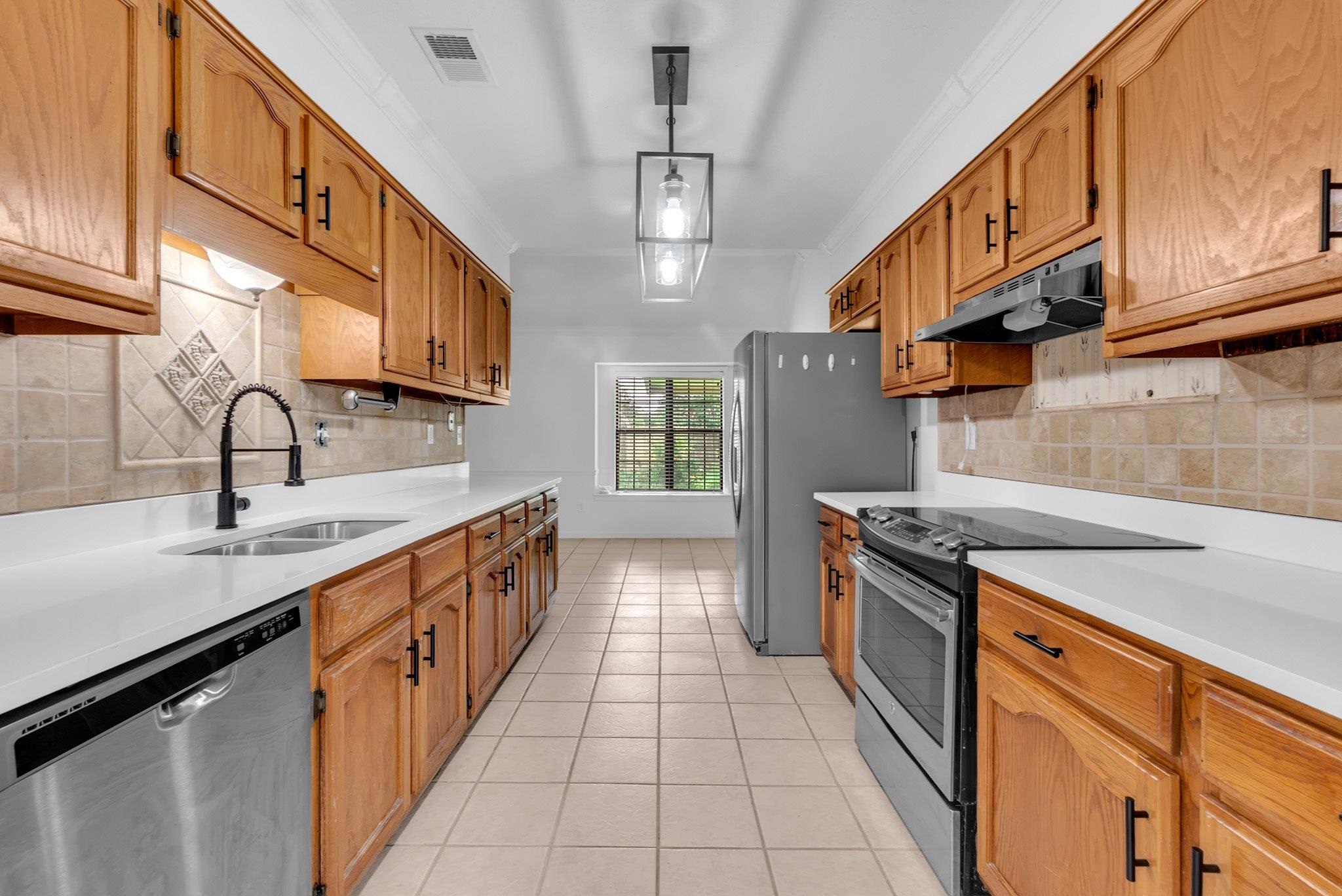 6613 Stephan Ridge Drive Bartlett, TN 38135 - Photo 8 of 24 Galley kitchen featuring wood cabinetry, light countertops, a tile backsplash, and stainless steel appliances