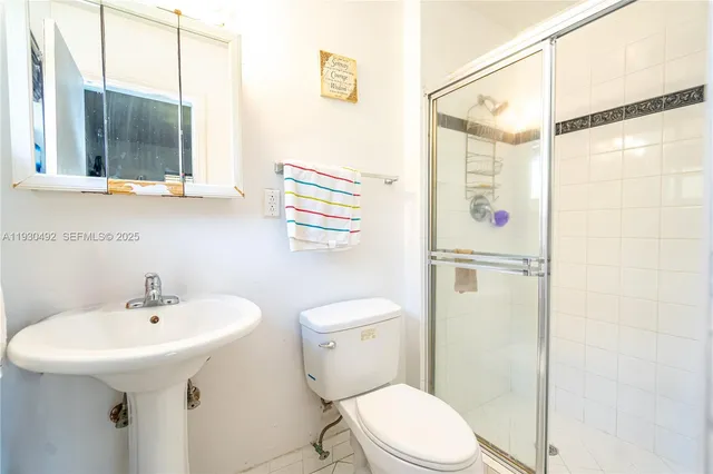 a bathroom with a sink a mirror a toilet and shower