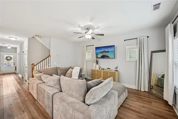 a living room with furniture kitchen area and a wooden floor