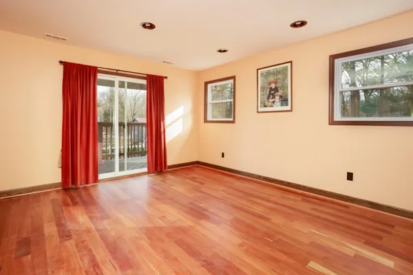a view of an empty room with window and wooden floor