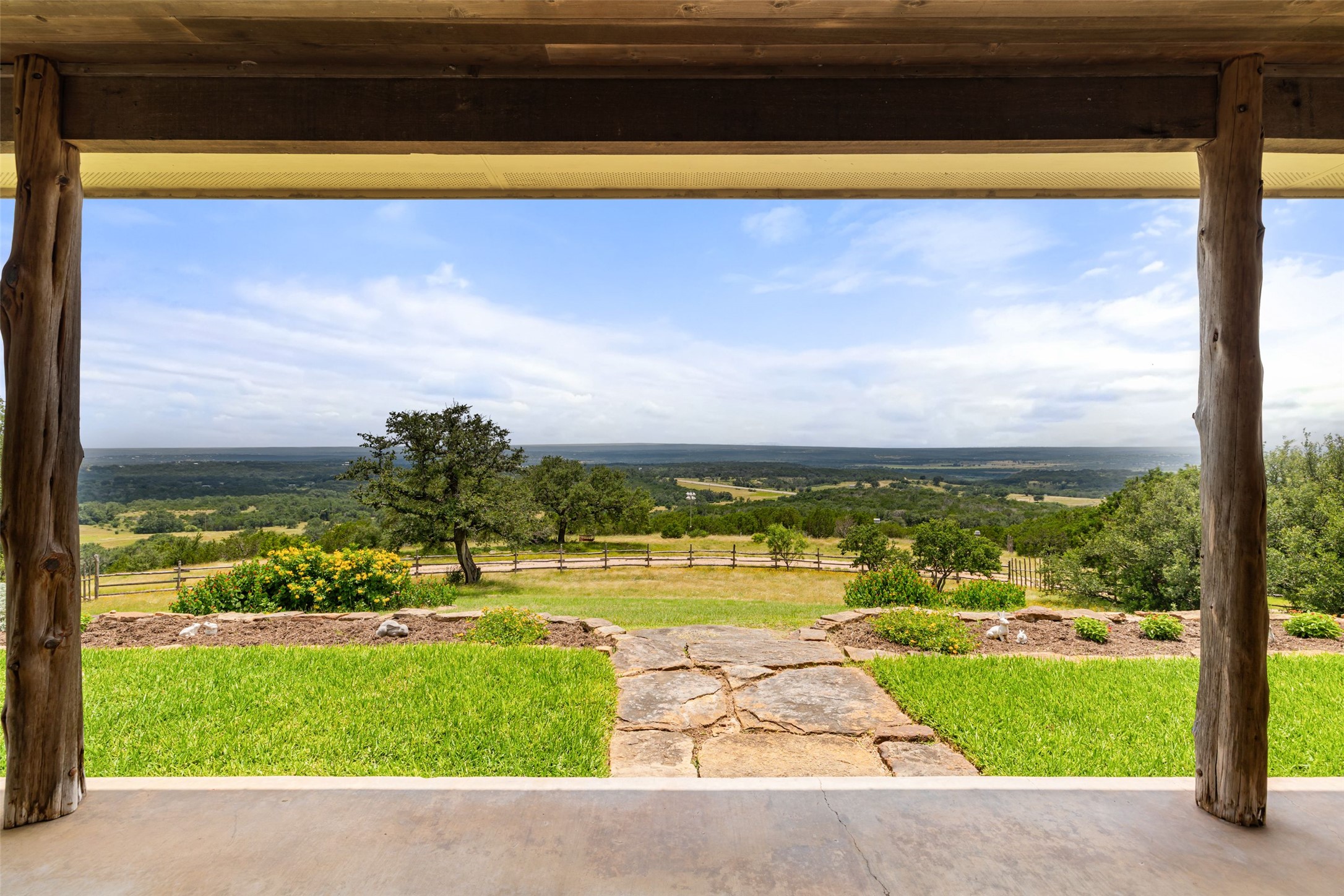 8400 Ranch Road 1431 Marble Falls, TX 78654 - Photo 6 of 30 A sprawling countryside view extends beyond the inviting stone pathway, bordered by lush green lawns and vibrant plantings.