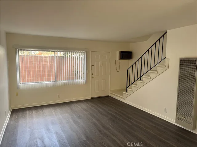 a view of an empty room with wooden floor and fan