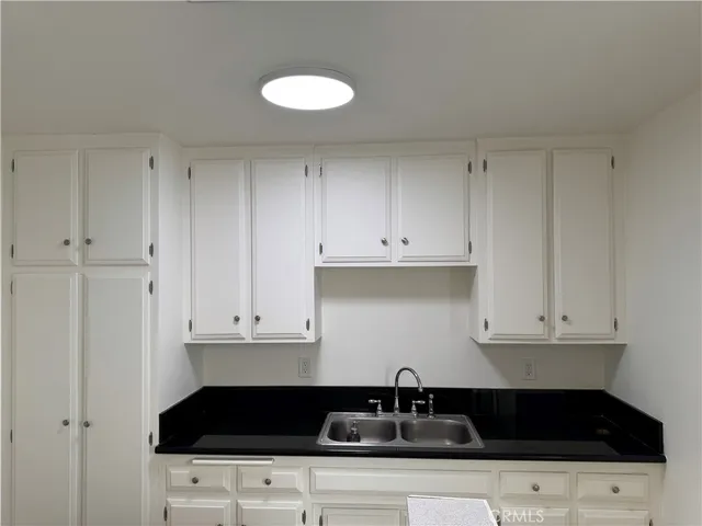 a kitchen with granite countertop white cabinets and black appliances