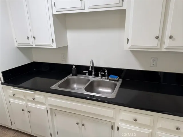 a kitchen with white cabinets and sink