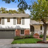 a front view of a house with a garden and tree