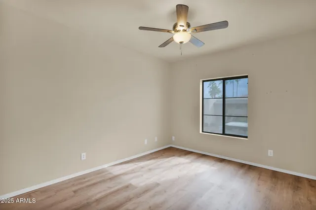 an empty room with wooden floor chandelier fan and windows
