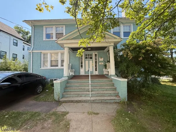 a view of a white house with a large windows and flower plants