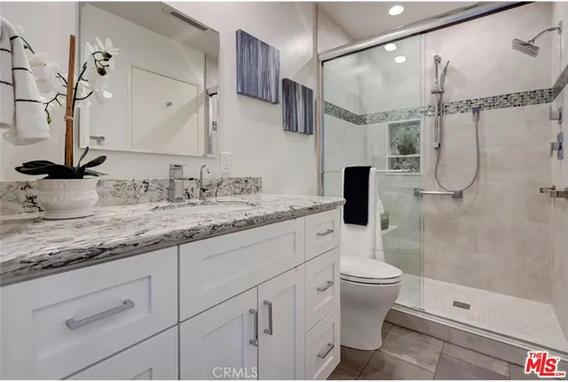 a bathroom with a granite countertop sink a toilet and shower