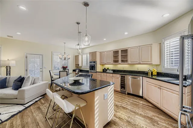 a kitchen with stainless steel appliances granite countertop a stove a sink a refrigerator a center island a dining table and chairs