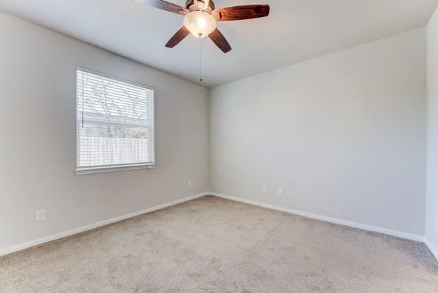 an empty room with a window and a fan