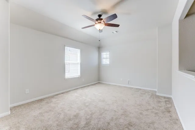 an empty room with fan and windows