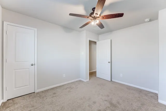 a view of an empty room and chandelier fan