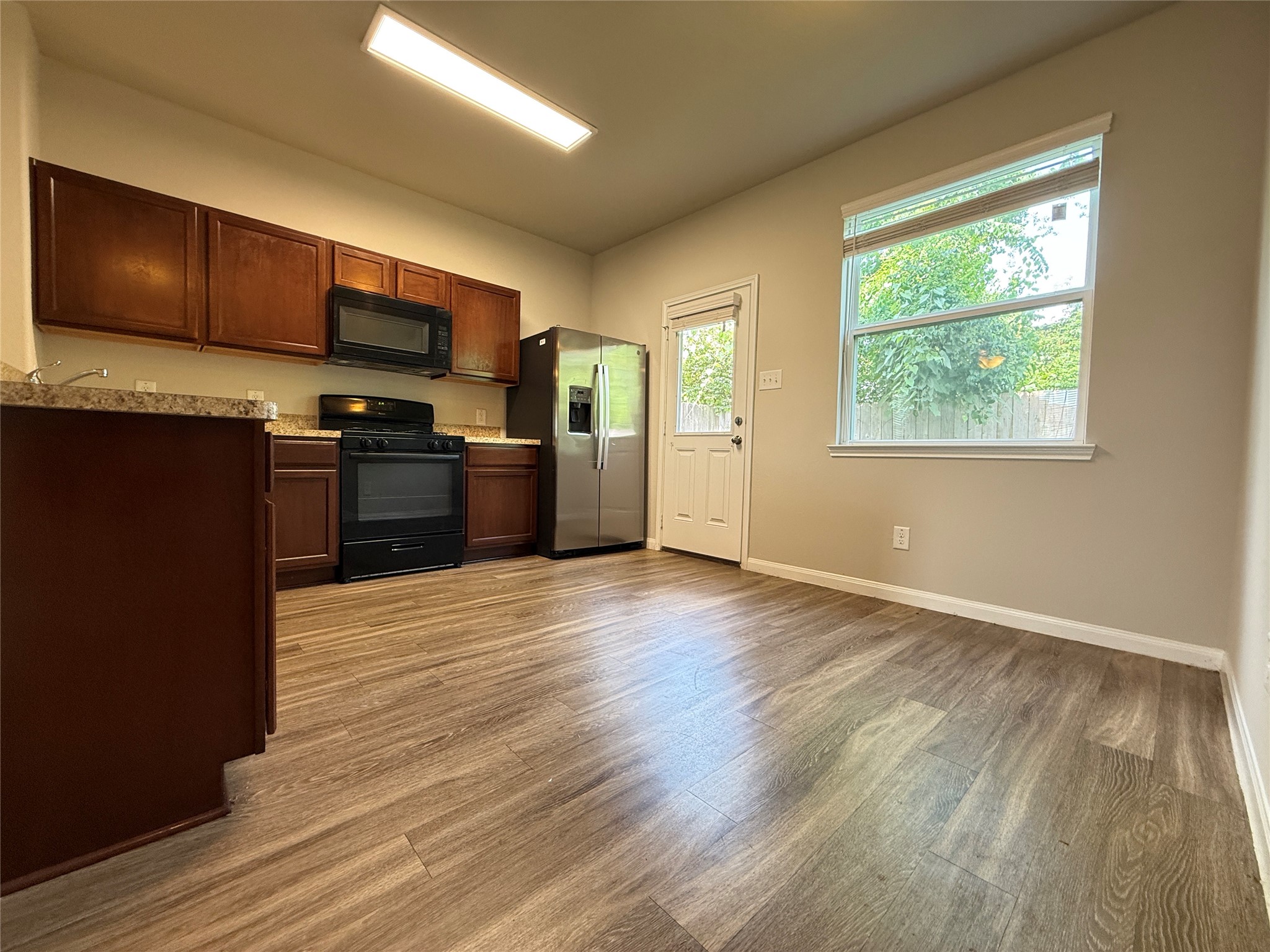 5842 Adelaide River Drive Katy, TX 77449 - Photo 10 of 40 a large kitchen with stainless steel appliances granite countertop a stove a refrigerator a sink dishwasher and wooden cabinets with wooden floor