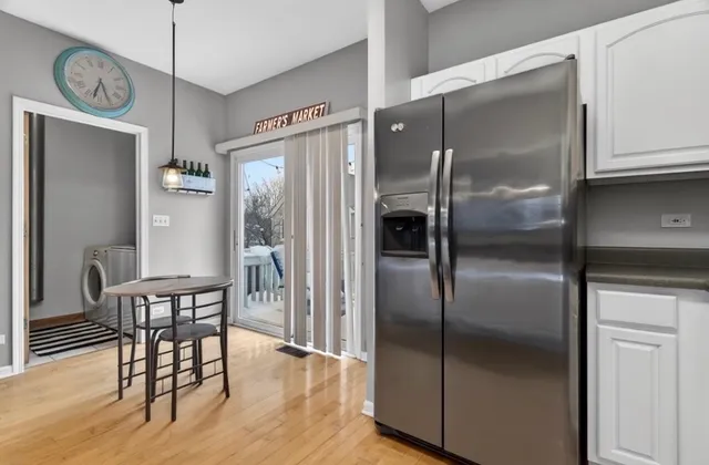 a kitchen with stainless steel appliances granite countertop a refrigerator a stove a dining table and chairs with wooden floor