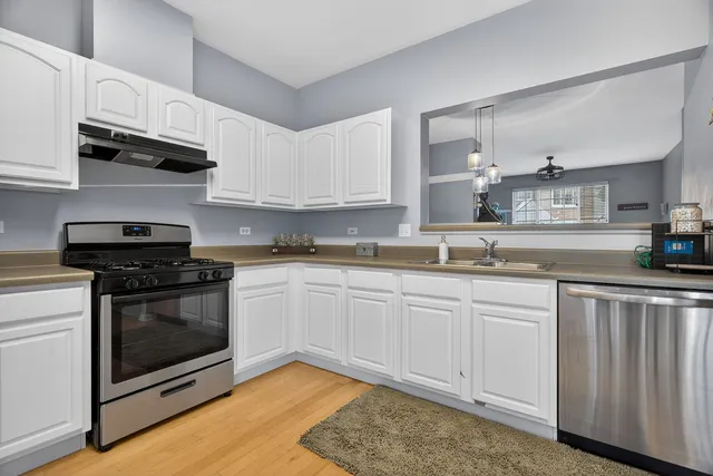 a kitchen with stainless steel appliances granite countertop a stove a sink and a white cabinets
