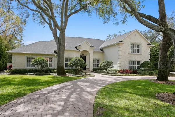 a front view of a house with a garden and trees