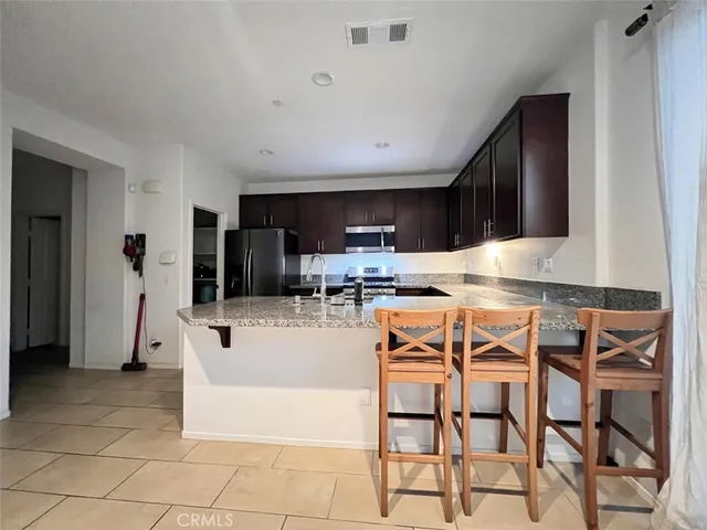 a kitchen with stainless steel appliances granite countertop a stove top oven a sink a dining table and chairs