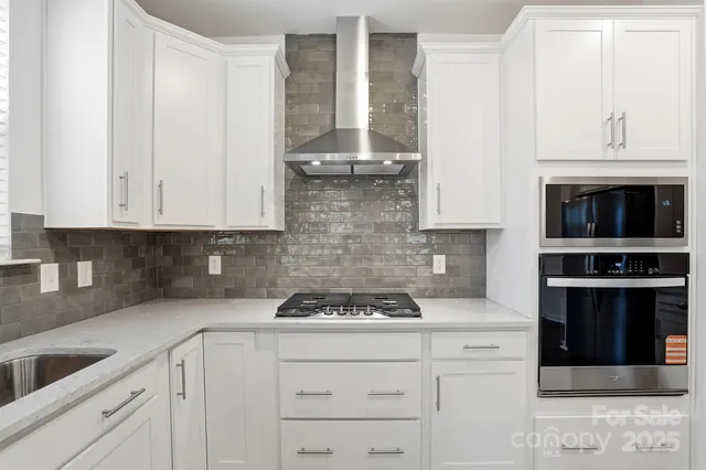 a kitchen with granite countertop white cabinets and stainless steel appliances