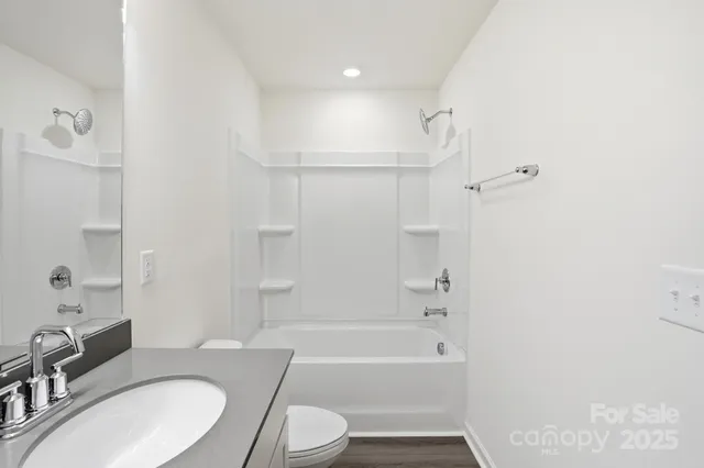 a bathroom with a granite countertop bathtub shower sink vanity mirror and toilet