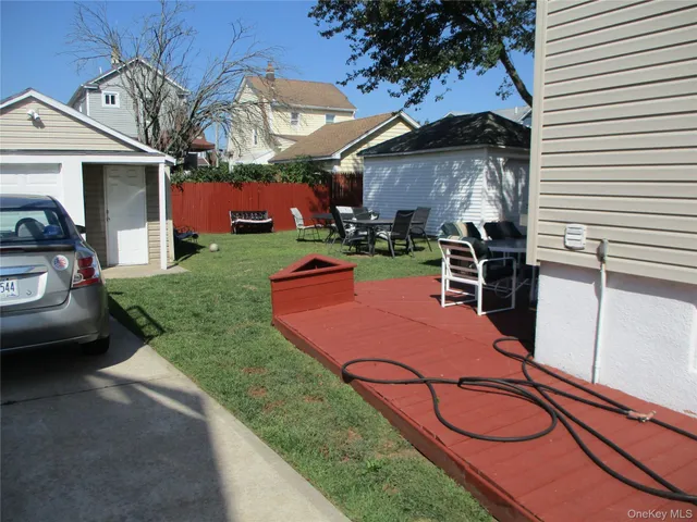 a view of a backyard with couches table and chairs under an umbrella