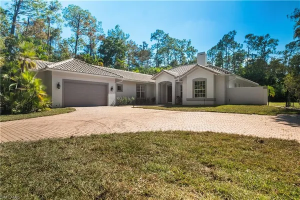 a front view of a house with a yard and trees